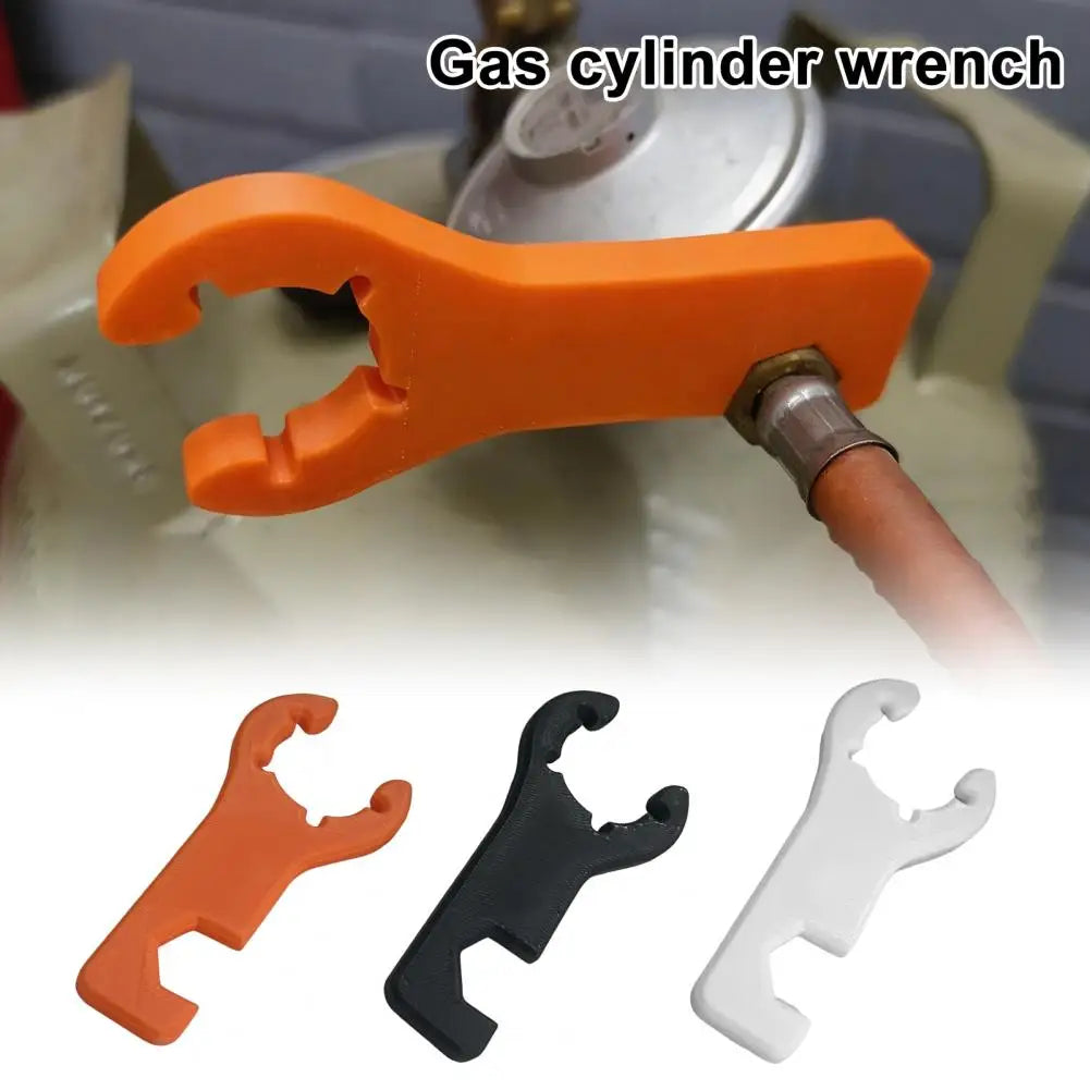 Orange gas cylinder wrench in use tightening a gas valve fitting on a green LPG cylinder close-up