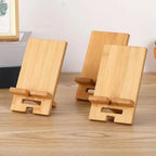 Bamboo wood desktop phone stand holding a smartphone upright on a timber desk in a natural home office setting