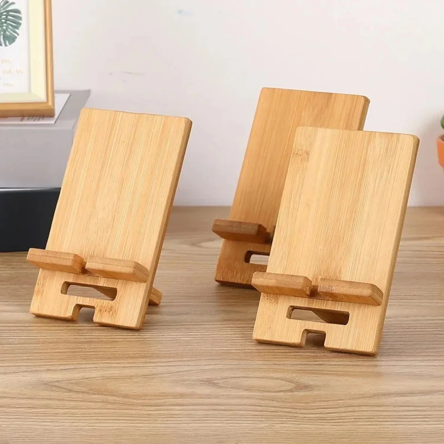 Bamboo wood desktop phone stand holding a smartphone upright on a timber desk in a natural home office setting