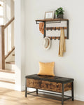 Wall-mounted coat rack with top shelf, hanging rod, and two rows of black hooks in rustic brown and black, styled in a bright hallway with coats and scarves