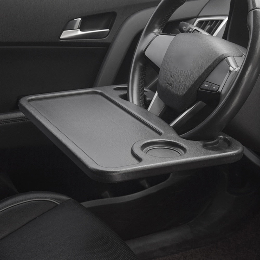 Car steering wheel table clipped to black steering wheel with laptop computer on surface