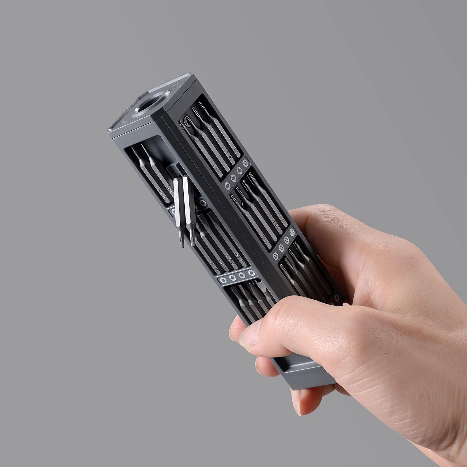 Precision screwdriver set with magnetic bits held in hand showing full moulded storage case, grey background