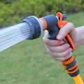 Garden spray gun orange black ABS plastic being used outdoors showing water spray pattern