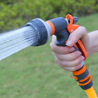Garden spray gun orange black ABS plastic being used outdoors showing water spray pattern