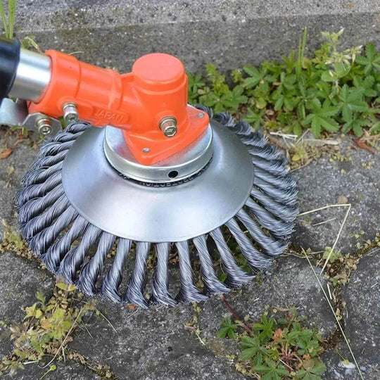 Steel wire brush trimmer head attached to orange electric trimmer on concrete surface