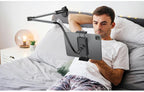 Black gooseneck tablet phone stand with desk clamp holding iPad in bedroom setting with person reading