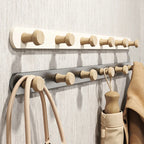 White and grey wall coat racks with wooden knob hooks mounted on a textured wall, coats and bags hanging in use
