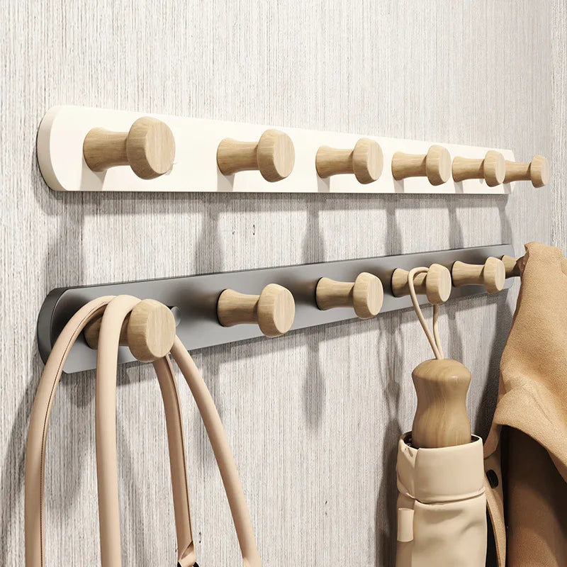 White and grey wall coat racks with wooden knob hooks mounted on a textured wall, coats and bags hanging in use