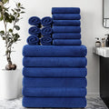 18-piece towel set in navy blue stacked and rolled in a modern bathroom with marble bench and indoor plant