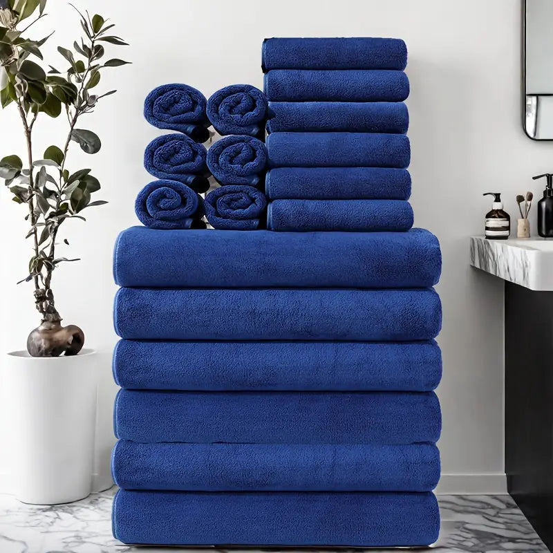 18-piece towel set in navy blue stacked and rolled in a modern bathroom with marble bench and indoor plant