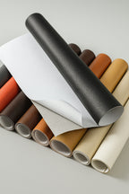 Self-adhesive leather repair patch in black laid flat on white background showing texture and adhesive side