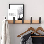 Wall-mounted wooden coat rack with black metal hooks holding coats and hangers in a hallway setting