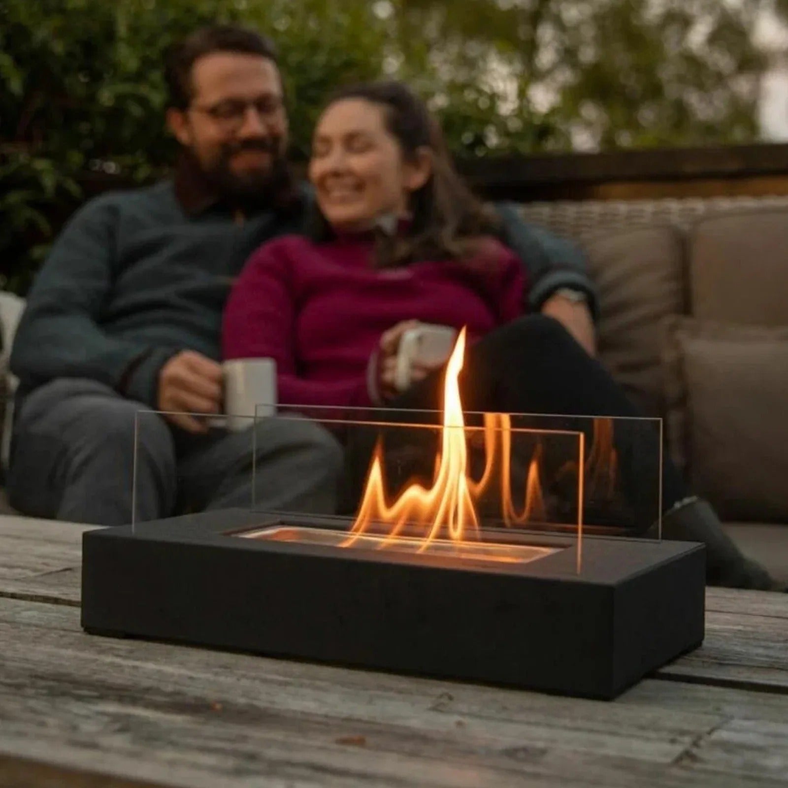 Tabletop bio-ethanol fire bowl with flames burning on wooden deck outdoor entertaining setting