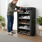 Man rolling up black fabric dust cover on freestanding shoe rack with five tiers of shoes in bright entryway