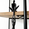 Black resin abstract connected souls sculpture with two intertwined figures, displayed on a natural wooden shelf in a lounge room setting