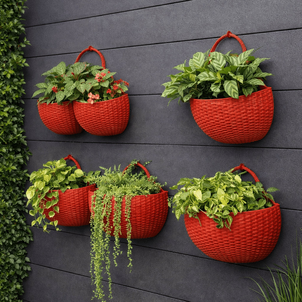 Wall-mounted rattan-style plant pots in red colour mounted on grey wooden wall with green plants