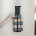 Hand accessing towel from black metal wire rack wall mounted bathroom organisation