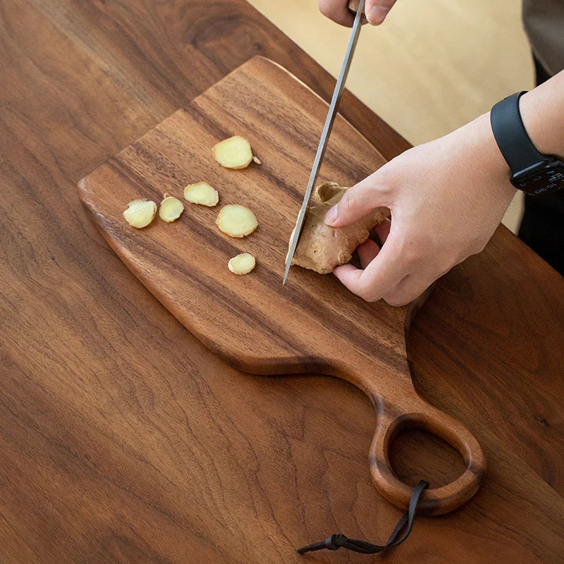 Hands slicing fresh ginger on walnut cutting board kitchen prep lifestyle shot