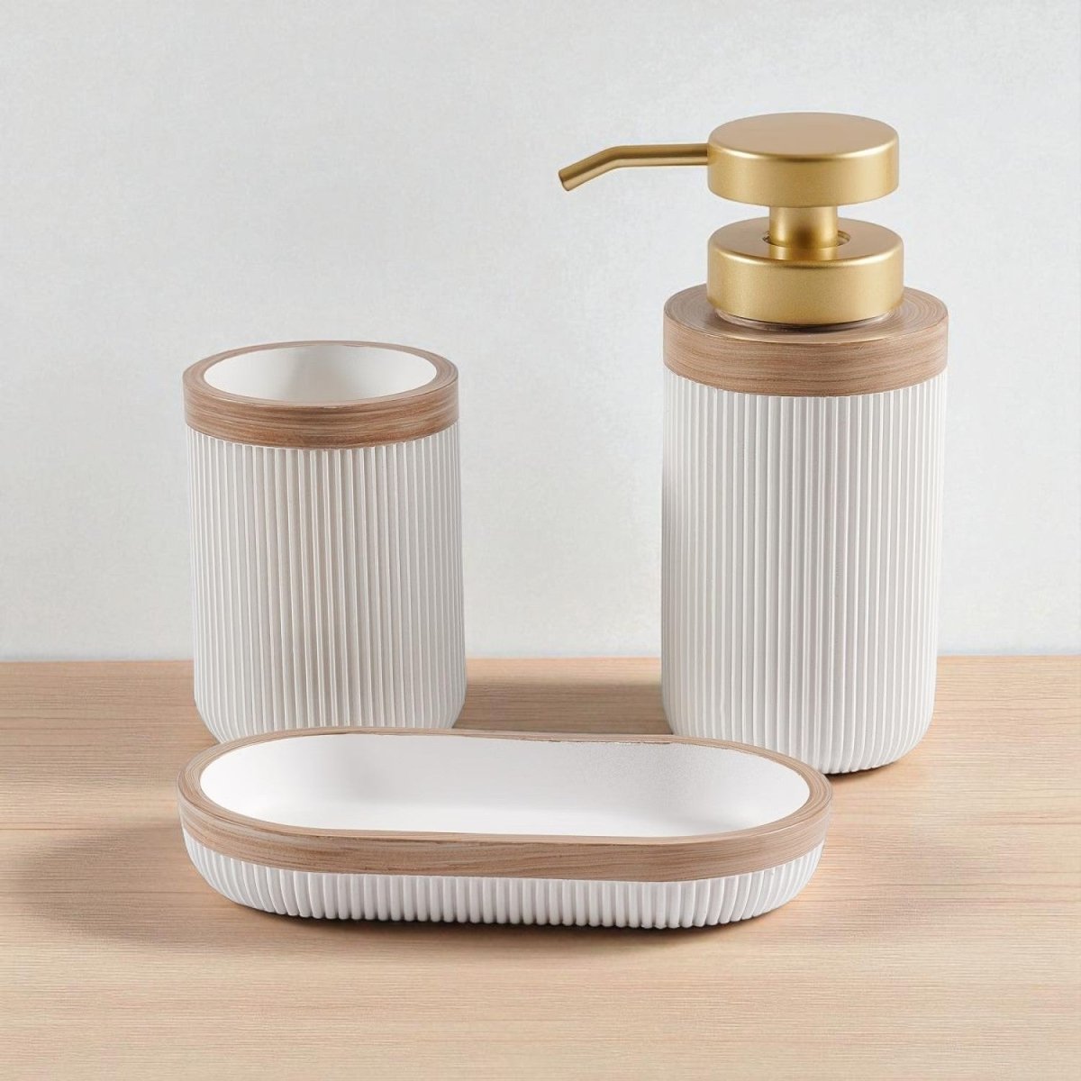 Soap dispenser, toothbrush cup and soap dish in white polyresin with wooden trim on white studio background