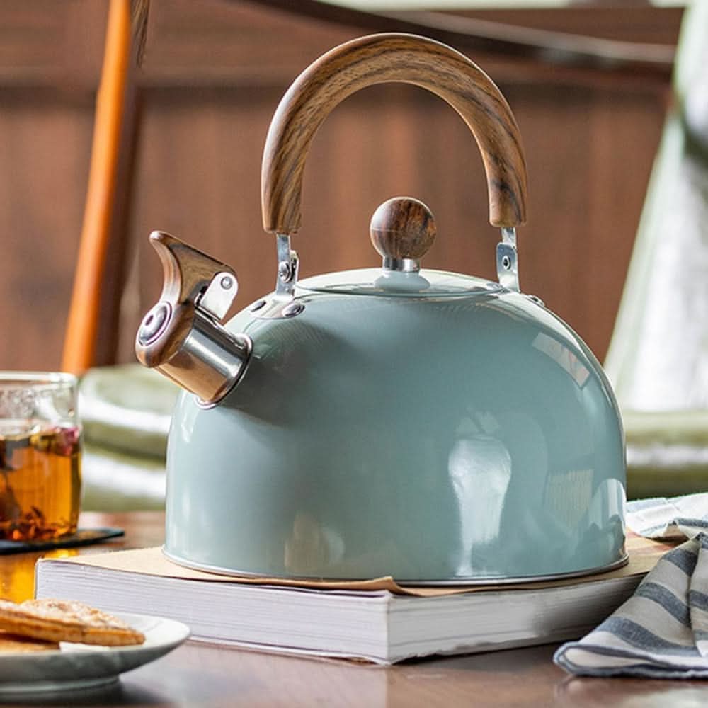 Light green stovetop whistling kettle with wooden handle on a timber bench in a bright Australian kitchen, lifestyle setting