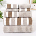 Stack of striped microfibre towels in coffee, taupe and white folded neatly beside a bathroom shelf with plants
