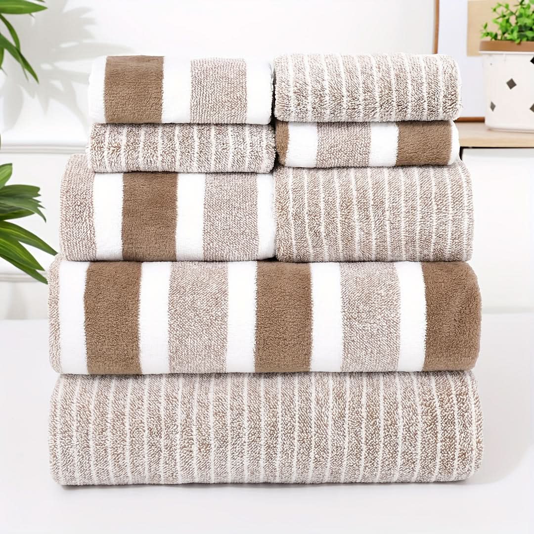Stack of striped microfibre towels in coffee, taupe and white folded neatly beside a bathroom shelf with plants