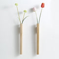 Two slim wooden hanging wall vases one dark walnut one light beech on pure white studio background