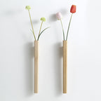 Two slim wooden hanging wall vases one dark walnut one light beech on pure white studio background