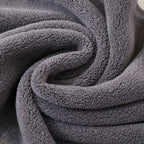 18-piece grey towel set stacked in a styled neutral bathroom with black towel rail and white tiles
