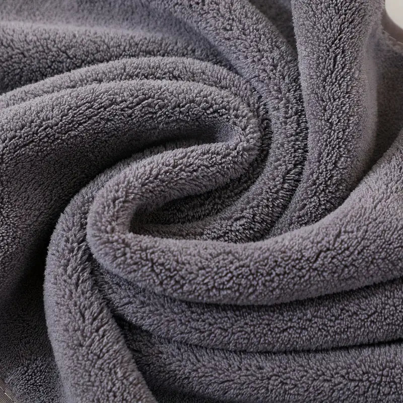 18-piece grey towel set stacked in a styled neutral bathroom with black towel rail and white tiles