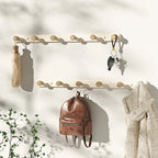 Grey wall coat rack with wooden knob hooks in Scandinavian entryway, scarves and jacket hanging on wall