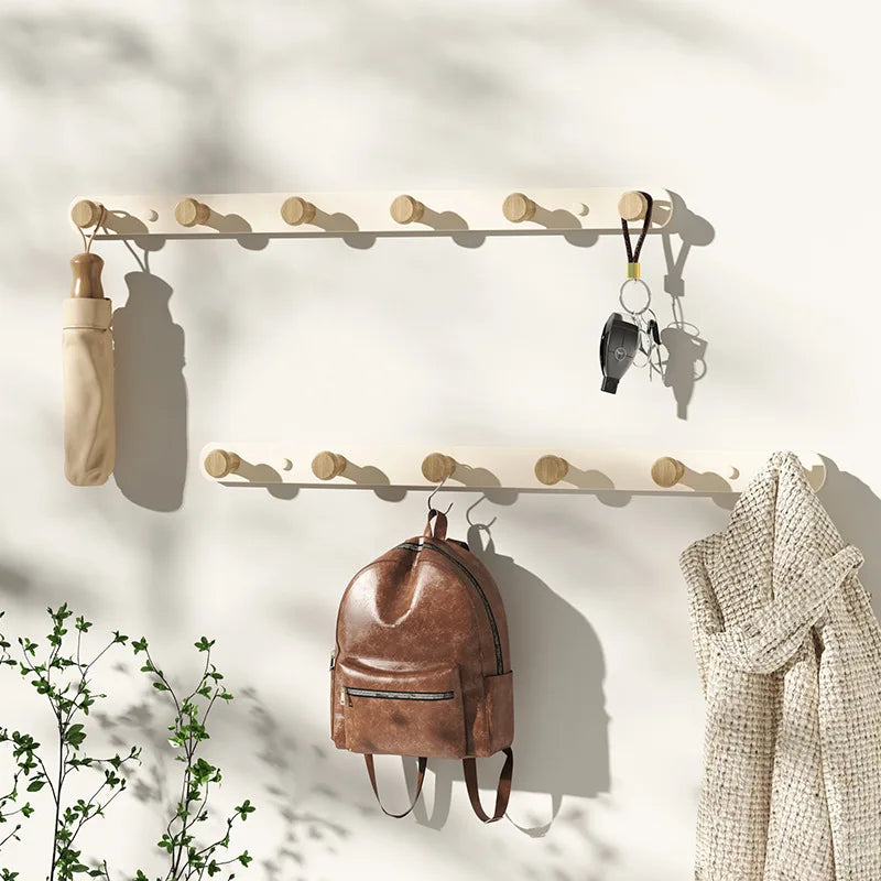 Grey wall coat rack with wooden knob hooks in Scandinavian entryway, scarves and jacket hanging on wall