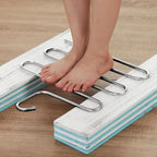 Set of three 5-layer stainless steel pants hangers on a rail, each loaded with folded trousers in a wardrobe