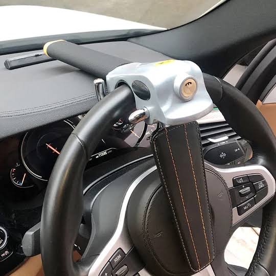 Steering wheel lock fitted in modern car interior showing adjustable universal design