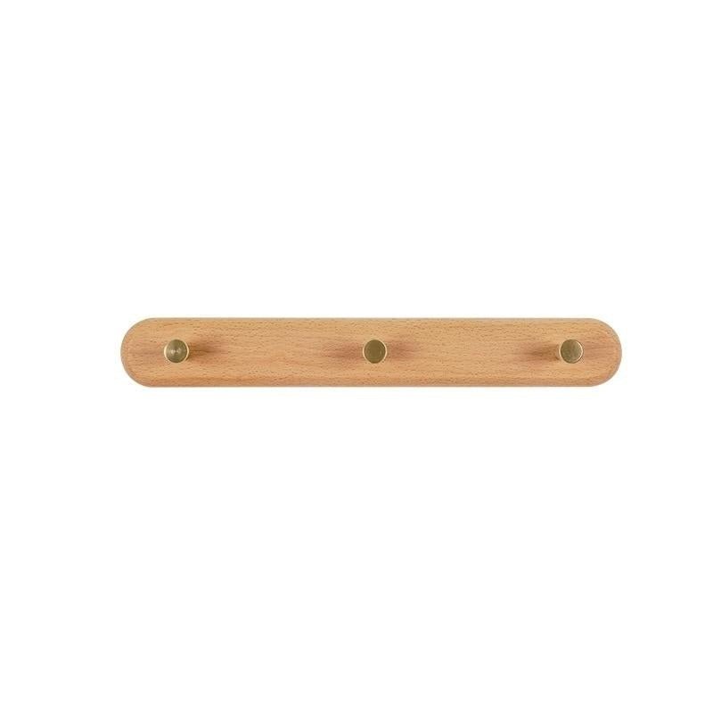 Walnut wood 3-hook coat rack on a light wall in a tidy bedroom, linen bag and scarf on hooks