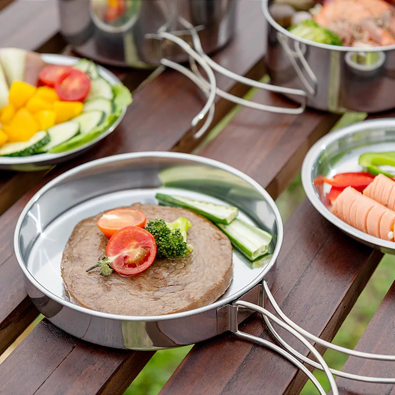 Stainless steel camping pot filled with corn and vegetable soup cooking outdoors on a riverside camp table