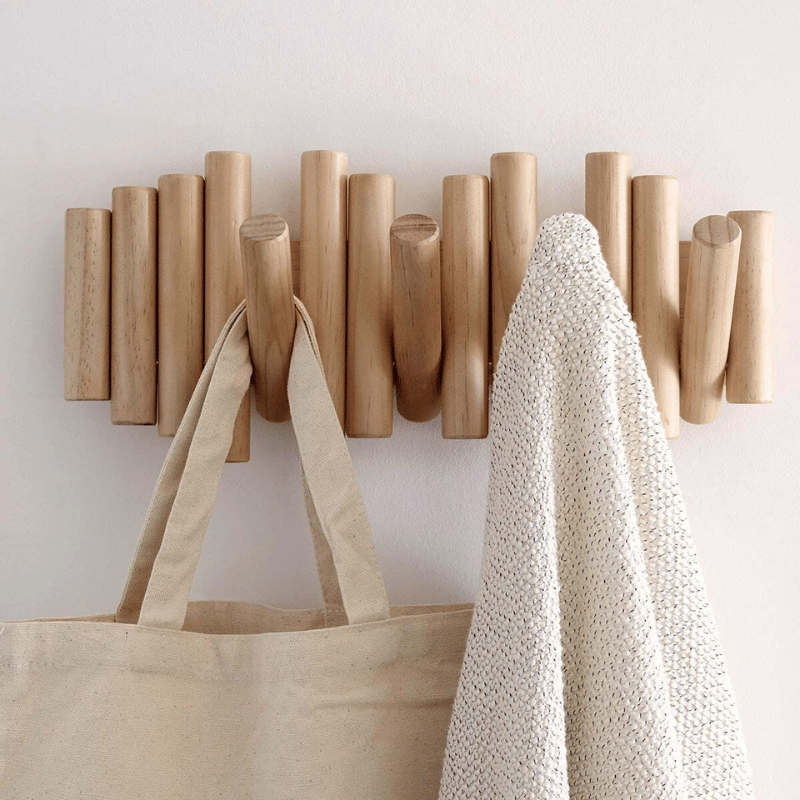 Wooden wall coat rack in minimalist AU entryway with white towel and woven bag on hooks, timber floorboards below, wide room view
