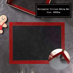 Black silicone baking mat on oven tray with unbaked cookie shapes, kitchen oven open in background