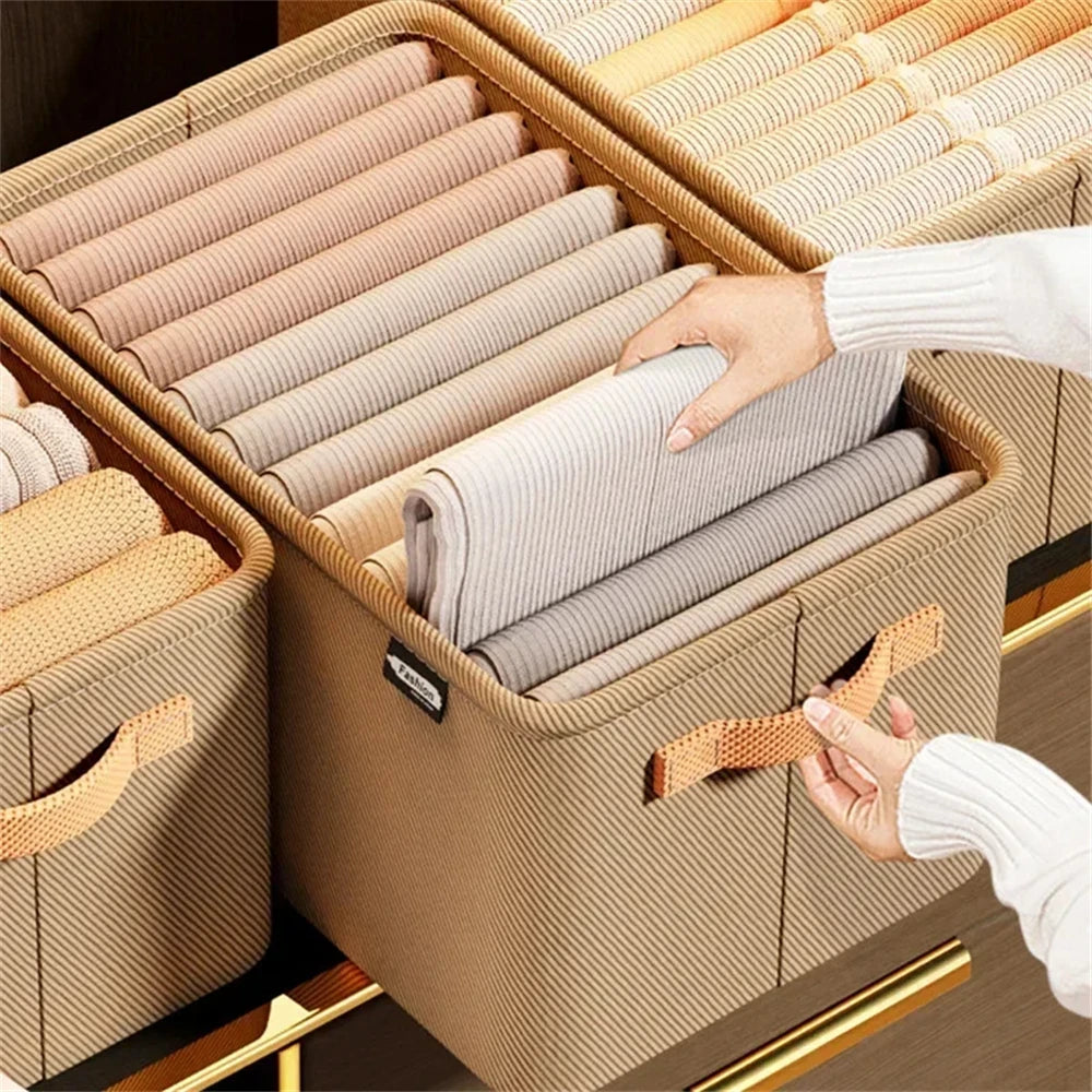 Grey fabric storage bins being pulled from wardrobe shelf using woven side handle close up