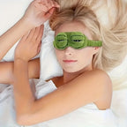 Close-up of 3D frog sleep mask showing embroidered cartoon eye detail and soft plush green fabric texture
