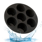 Silicone muffin mould loaded with seven egg tarts inside open green air fryer basket on kitchen bench