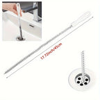 Hand inserting flexible drain hair removal brush into bathroom sink drain grey wall background