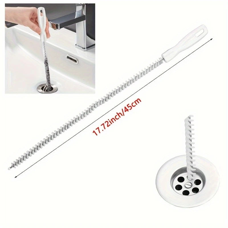 Hand inserting flexible drain hair removal brush into bathroom sink drain grey wall background