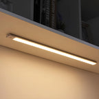 Motion sensor LED light under kitchen bench cabinet with hands reaching for storage items