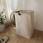 Beige foldable laundry basket with wooden handles beside a wooden shelf in a styled AU bedroom corner