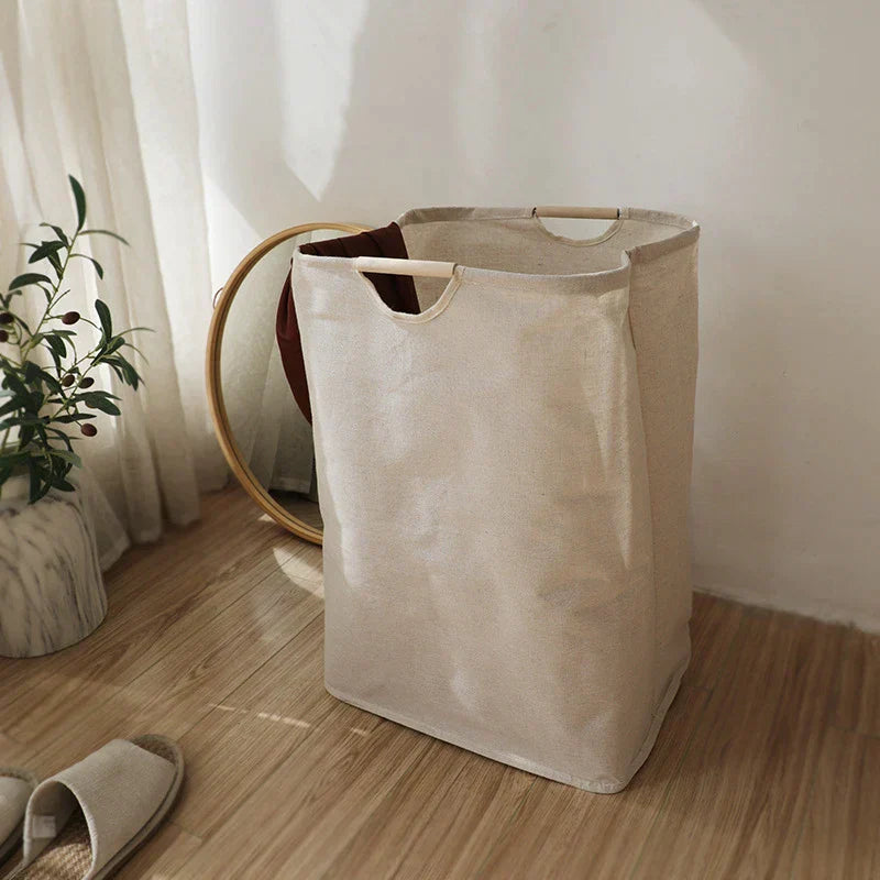 Beige foldable laundry basket with wooden handles beside a wooden shelf in a styled AU bedroom corner