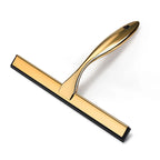 Hand using gold shower squeegee to wipe water from glass shower screen, bathroom setting