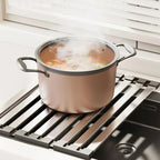 Hand placing hot cookware on heat-resistant over-sink drain rack surface during cooking