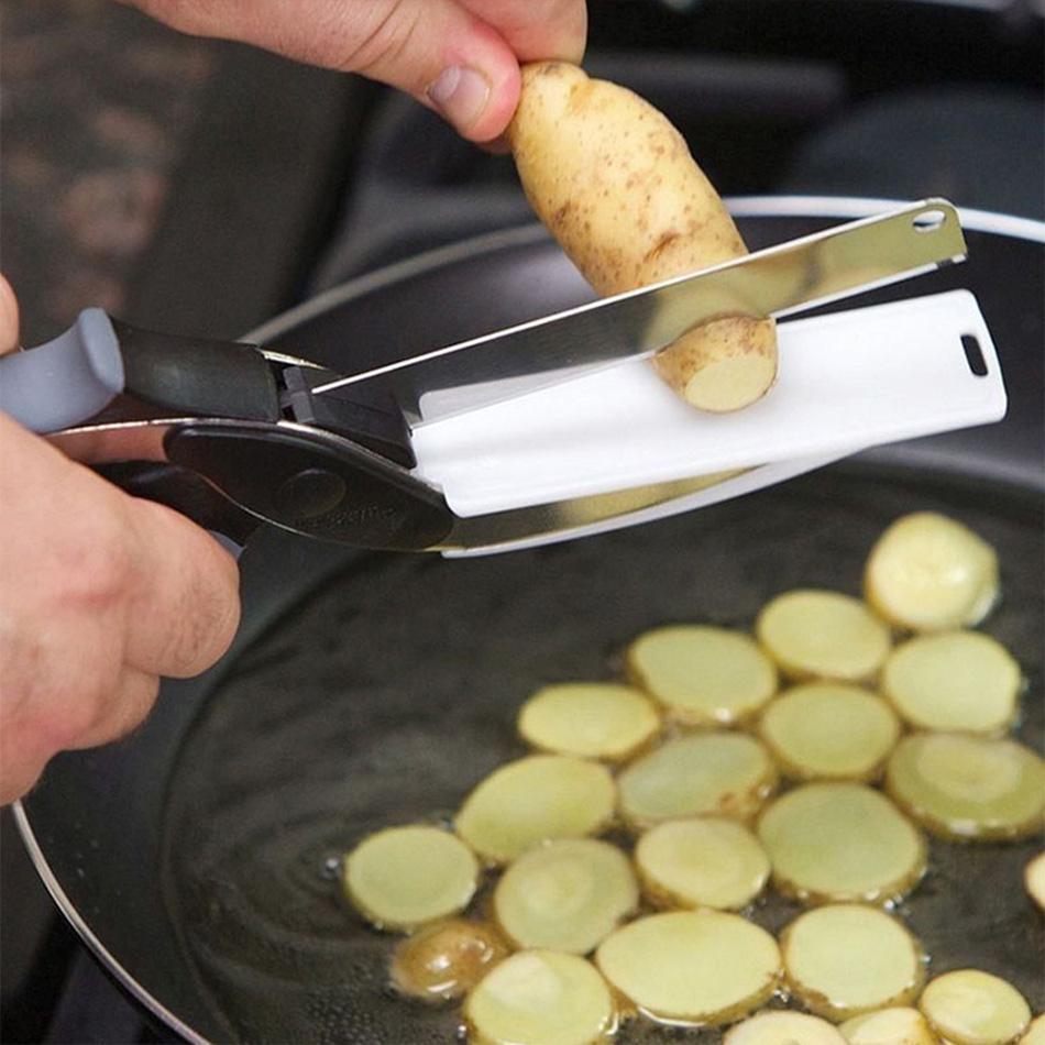 Hand cutting vegetables with kitchen scissors directly into red cooking pot