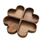 Overhead flat-lay of four walnut wooden snack bowls on linen tablecloth each filled with different snacks including pistachios and walnuts
